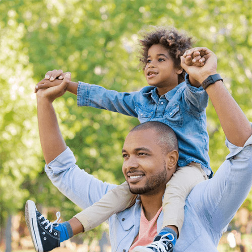 A father with his son on his shoulders, on a sunny day in the park
