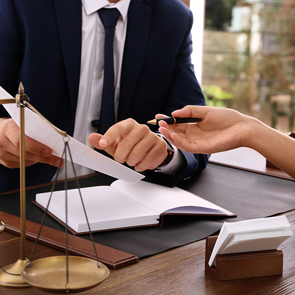 Lawyer working with client at table in office, focus on hands